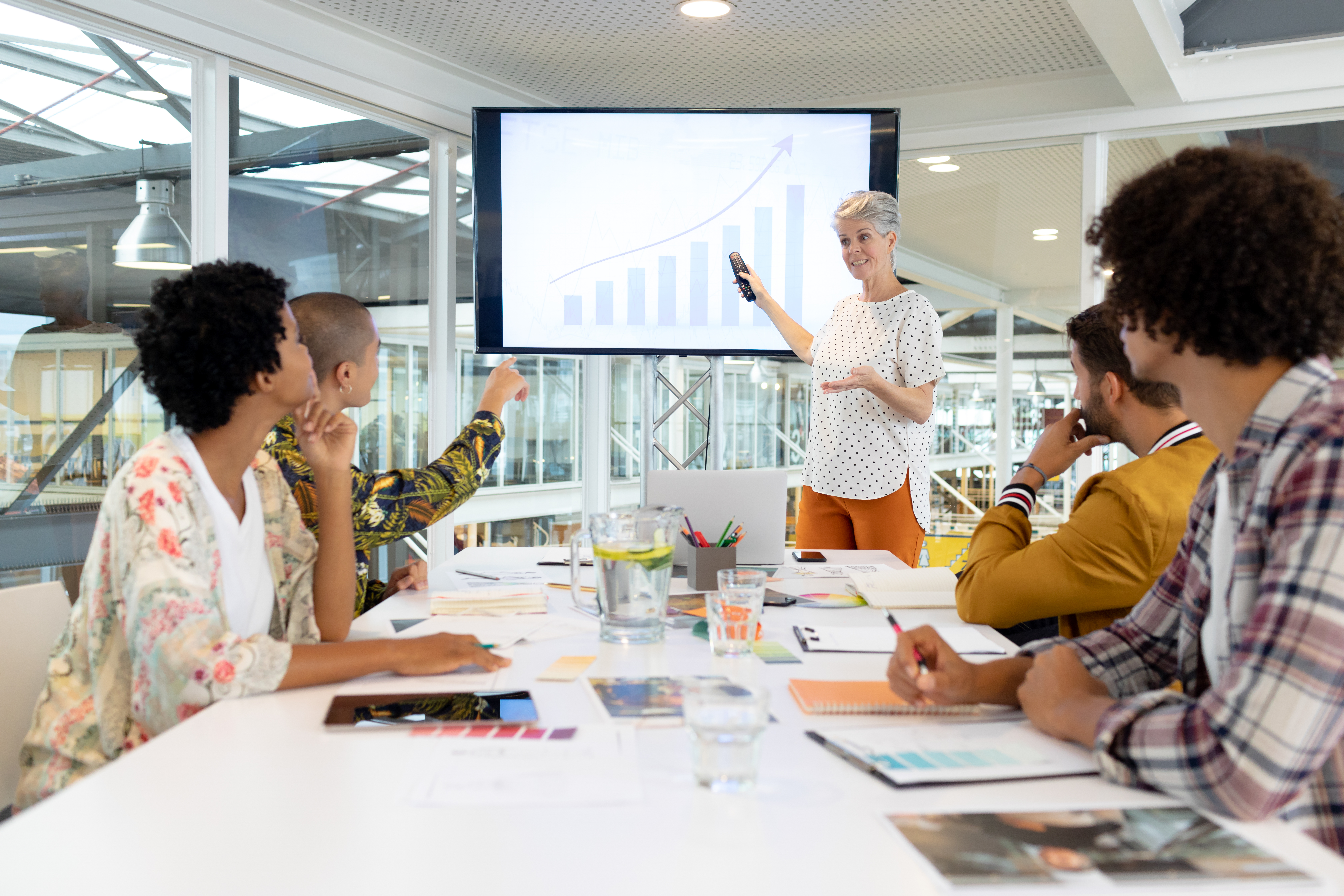 Front view of mature Caucasian businesswoman giving presentation on screen during meeting in a modern office